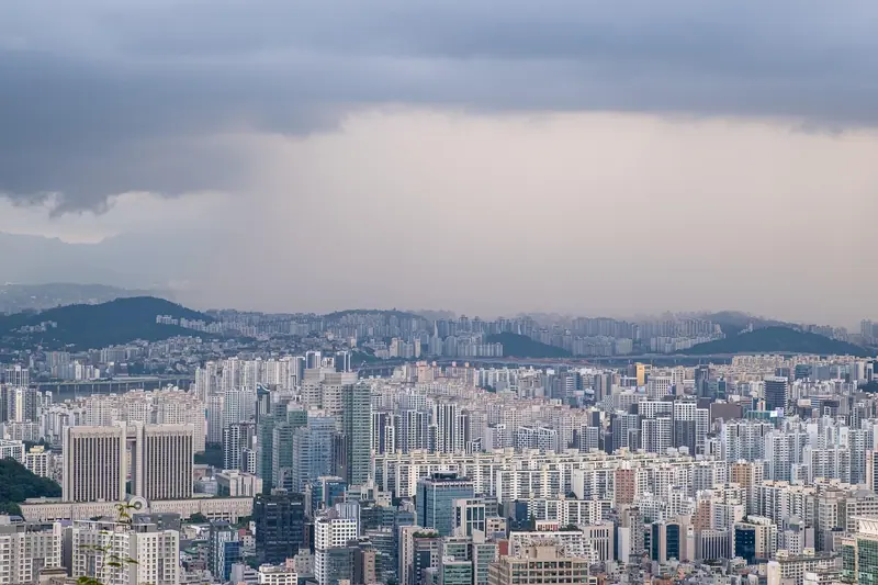 Vista do alto de uma cidade grande, com prédios até o horizonte e morros ao fundo
