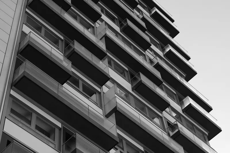 Varandas e janelas de um prédio residencial vistas de baixo, em preto e branco