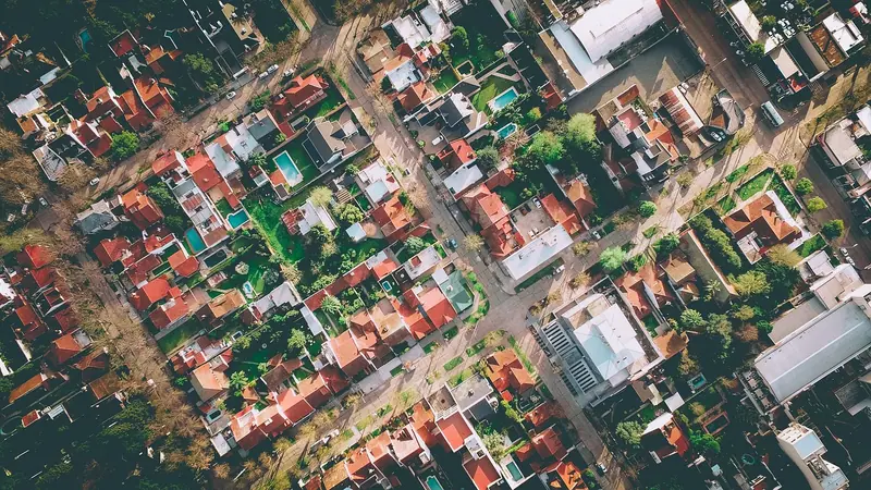 Vista aérea de um bairro com casas, quintais, piscinas, ruas e árvores
