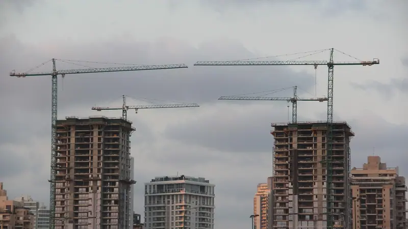 Prédios residenciais altos em construção, com guindastes no topo, ao lado de torres já prontas