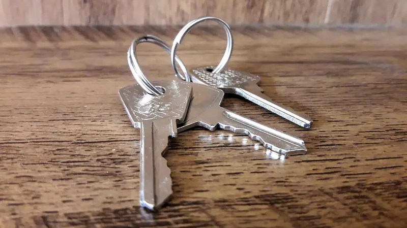 Duas chaves de casa num chaveiro, sobre uma mesa de madeira