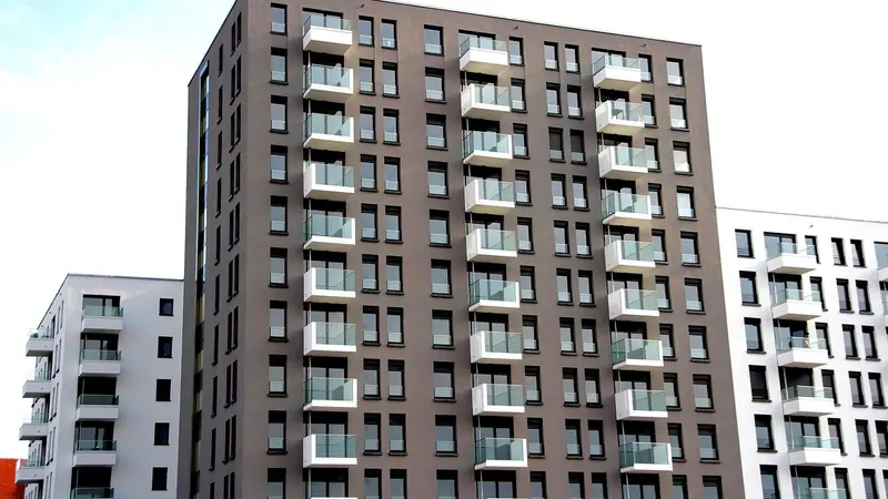 Prédio residencial novo de fachada escura com varandas, ao lado de outro prédio branco