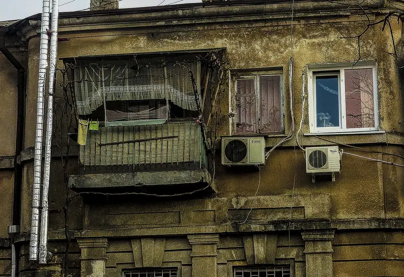 Fachada de prédio antigo com duas unidades de ar-condicionado presas na parede, perto das janelas