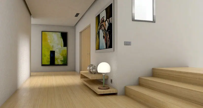 Hall de entrada com piso de madeira clara, quadros na parede, luminária e uma escada à direita