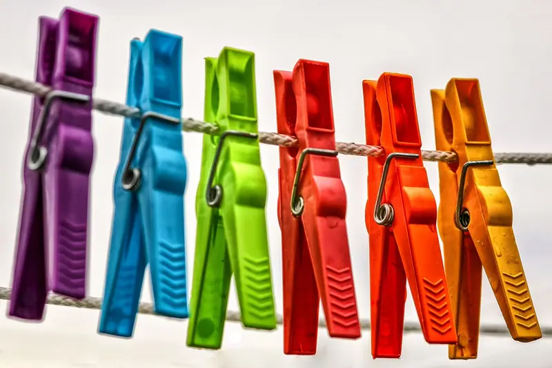 Prendedores de roupa coloridos enfileirados num varal, contra um fundo claro