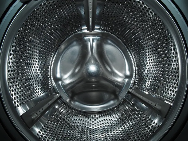 Interior do tambor de inox de uma máquina de lavar, com furinhos e aletas