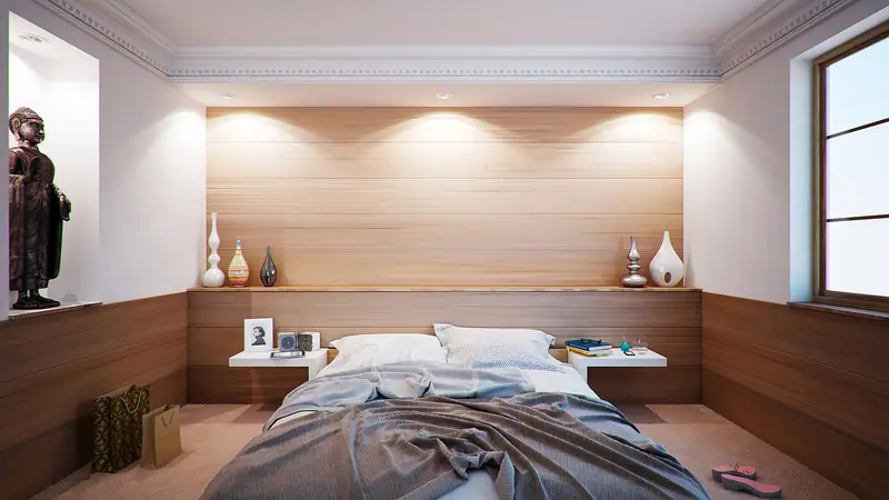 Quarto de casal com cabeceira de madeira iluminada e cama com cobertor cinza