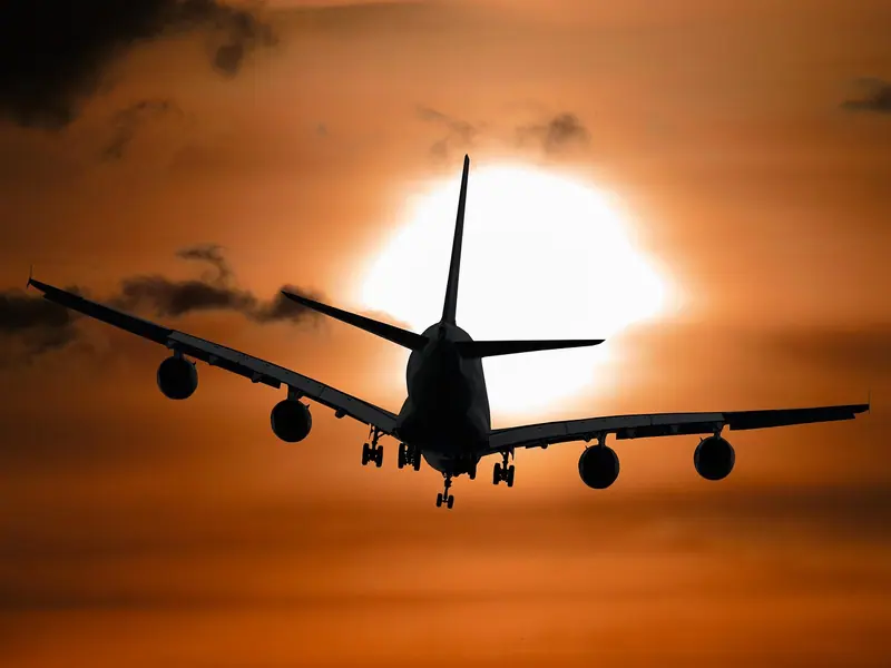 Silhueta de um avião de quatro motores passando na frente do sol