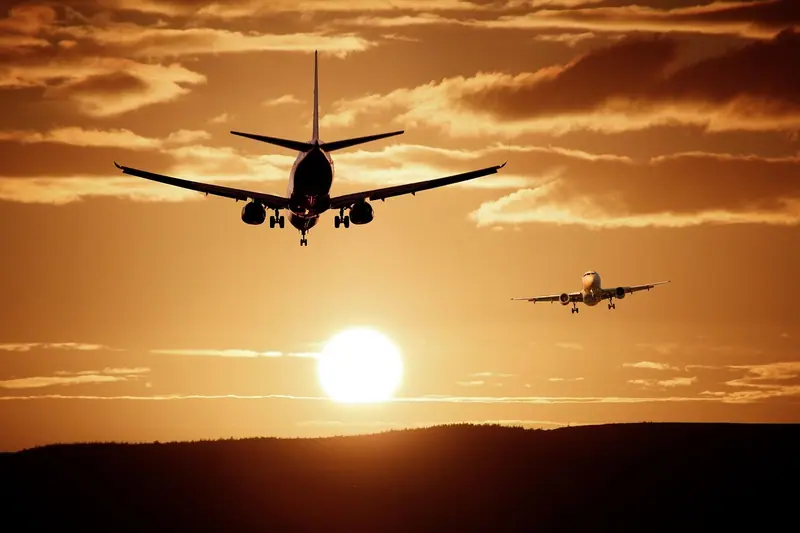 Dois aviões, um atrás do outro, descendo para pousar ao pôr do sol