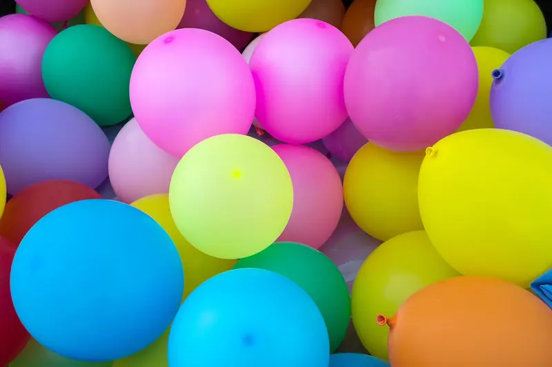 Muitos balões coloridos amontoados, em rosa, azul, verde e amarelo