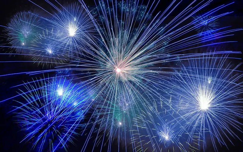 Fogos de artifício azuis e brancos se abrindo no céu à noite