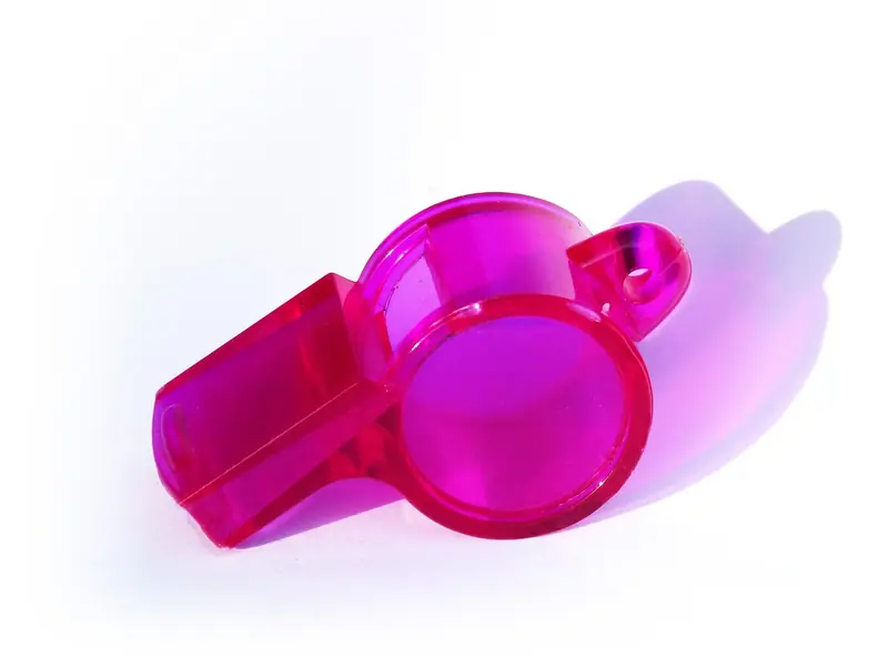 Apito de plástico rosa sobre um fundo branco