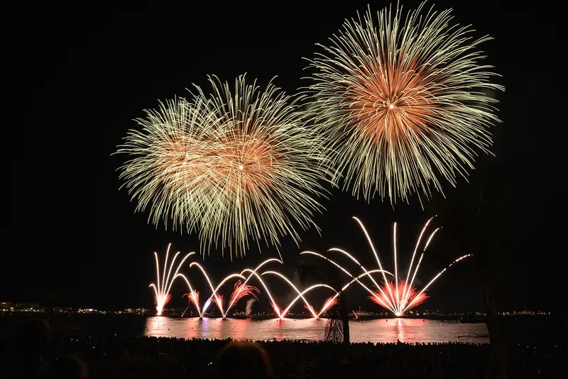 Fogos de artifício dourados estourando no céu noturno sobre a água