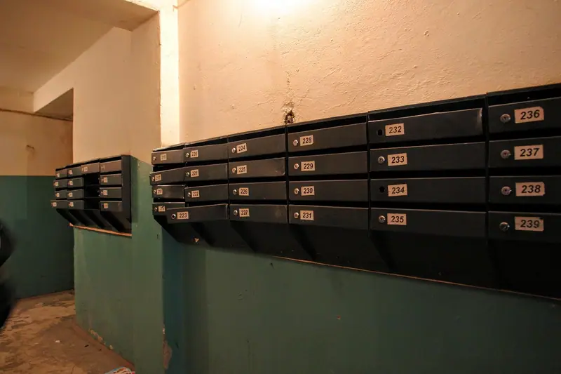 Caixas de correio metálicas numeradas na parede do hall de entrada de um prédio