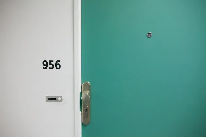 Porta de apartamento verde-água ao lado de uma parede branca com número
