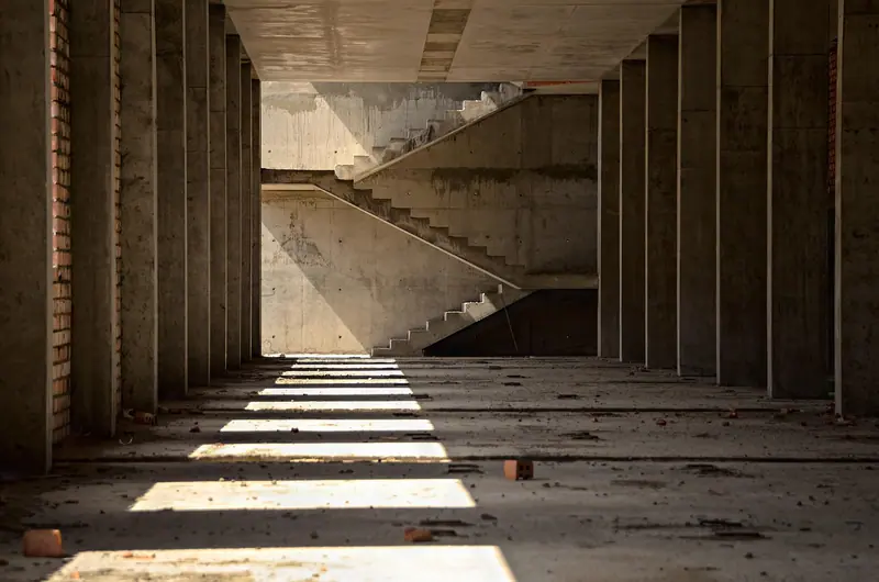 Andar vazio de um prédio em obra, com lajes, pilares e escada de concreto aparente