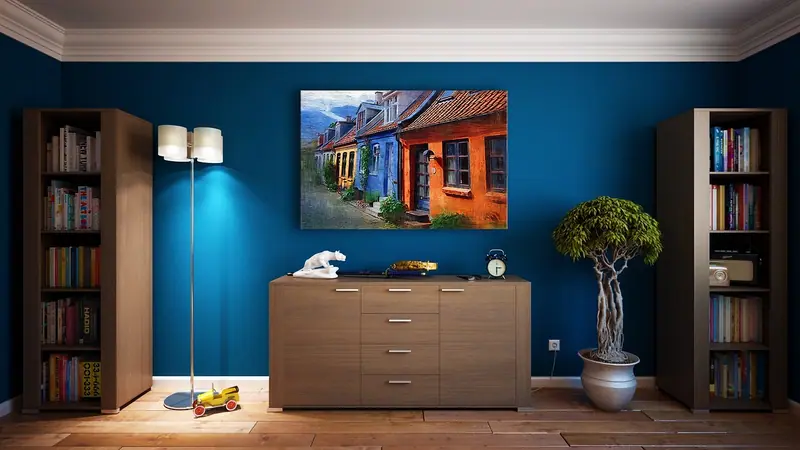 Sala com parede azul, cômoda de madeira, estantes de livros, luminária de piso e um vaso com planta