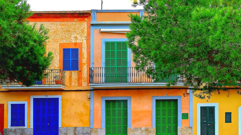 Fileira de casas coloridas de dois andares coladas umas nas outras, com portas e janelas verdes e azuis