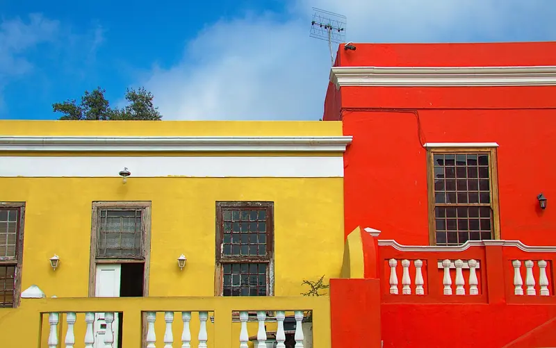 Duas casas vizinhas, uma amarela e outra vermelha, lado a lado e separadas só por uma parede