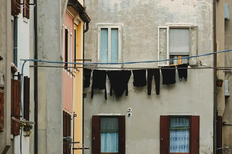 Duas fachadas muito próximas, com janelas e um varal de roupas estendido entre elas