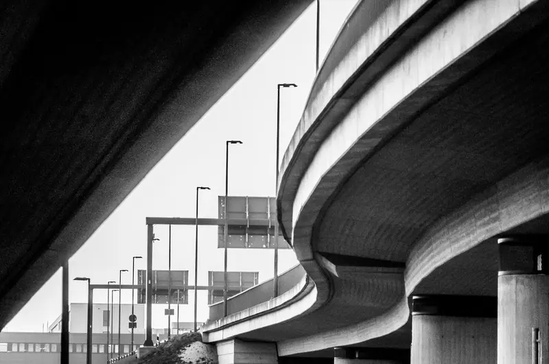 Via elevada de concreto em curva, vista de baixo, em preto e branco