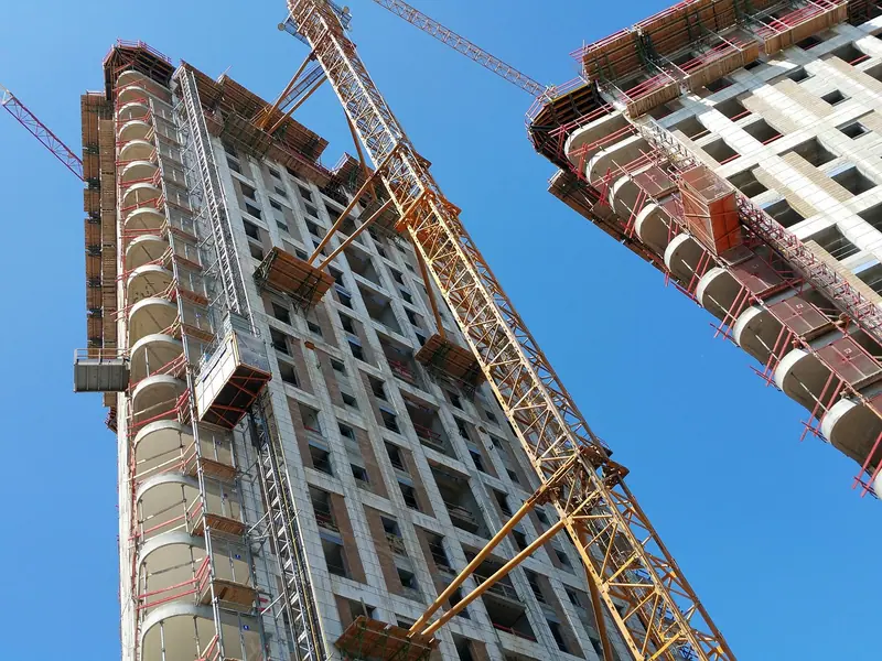 Prédio residencial em construção visto de baixo, com uma grua amarela ao lado