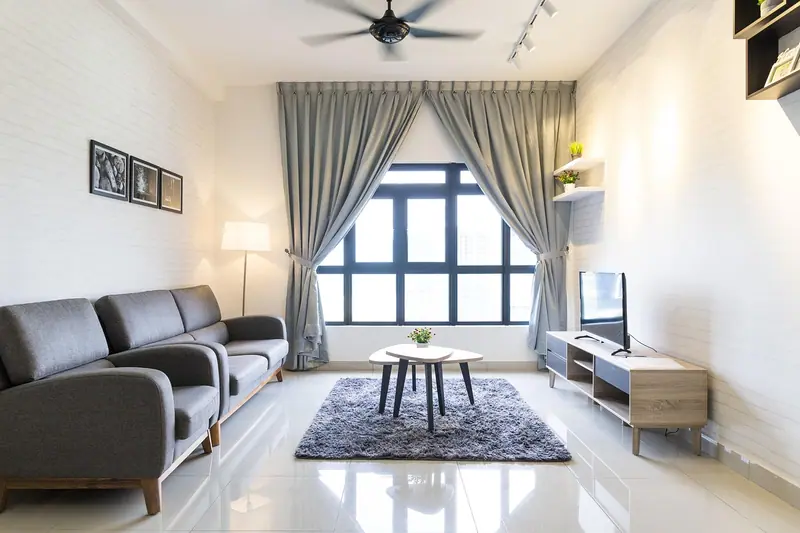 Sala com sofá cinza, tapete felpudo e cortinas longas na janela
