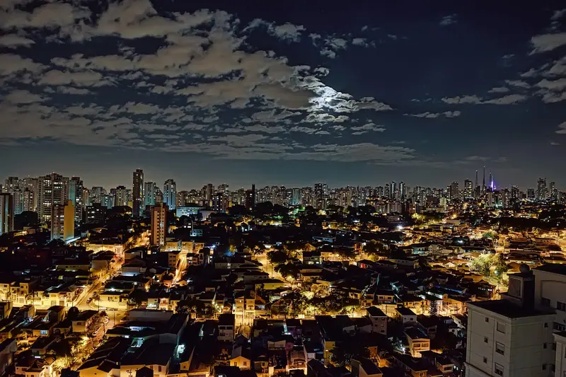Bairro de São Paulo visto do alto à noite, com casas e prédios iluminados até o horizonte