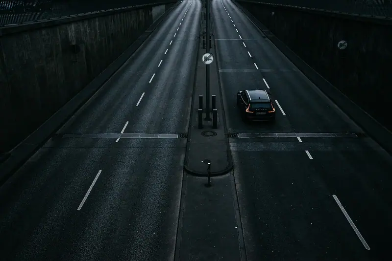 Avenida de várias faixas vista do alto à noite, com um único carro passando