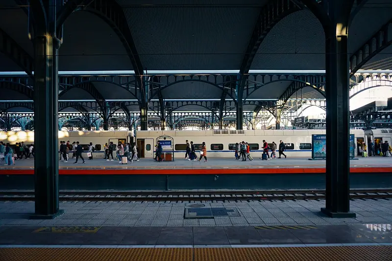 Plataforma de trem coberta, com pessoas esperando ao longe e um trem parado