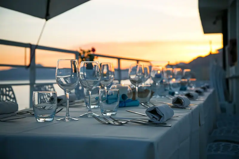 Mesa posta com taças e guardanapos num terraço de restaurante ao entardecer