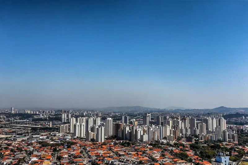 Vista ampla de São Paulo com casas de telhado vermelho em primeiro plano e prédios ao fundo