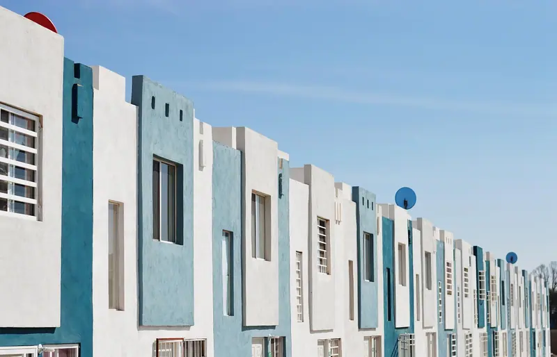 Fileira de casas coladas umas às outras, com janelas lado a lado na fachada