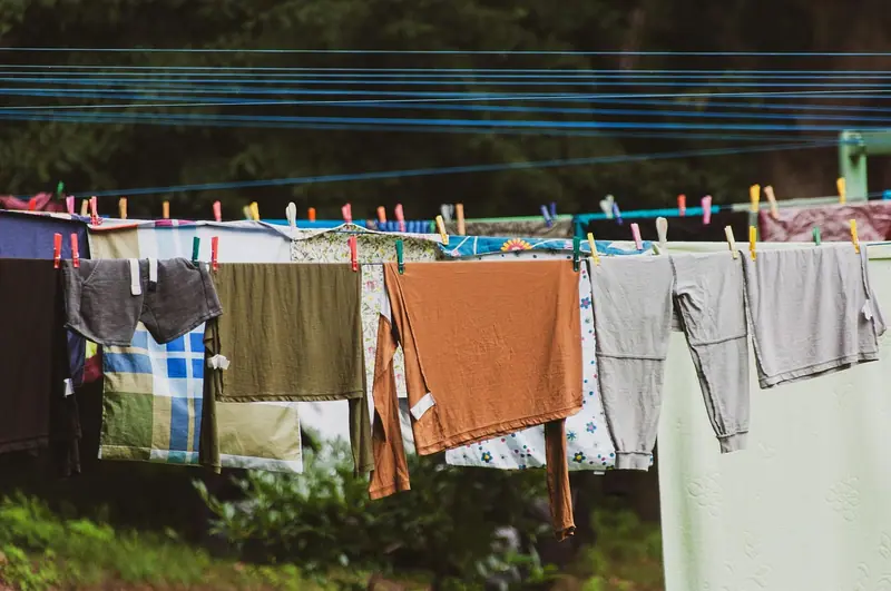 Varal com roupas coloridas presas por prendedores, estendido num quintal