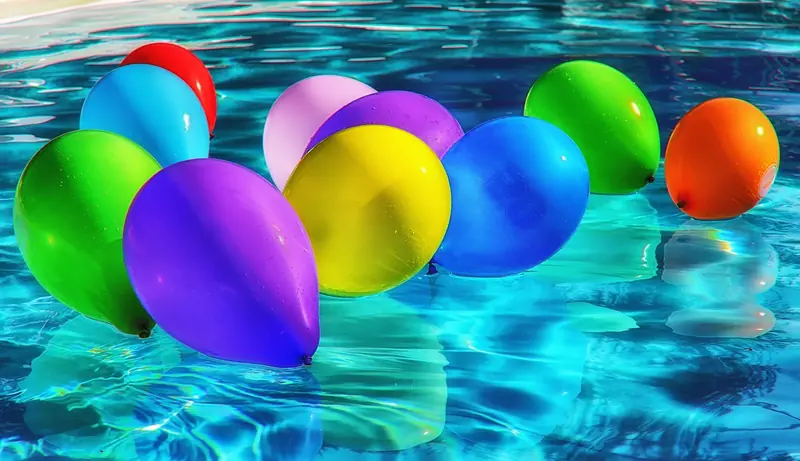 Balões coloridos boiando na água azul de uma piscina
