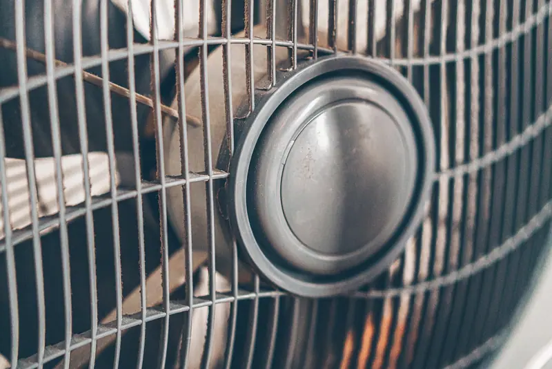 Grade e hélice de um ventilador elétrico vistas de perto