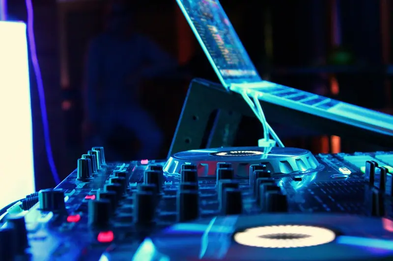 Mesa de som de DJ iluminada por luzes azuis numa festa