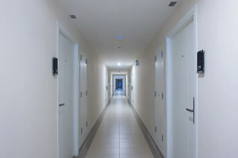 Corredor comprido de prédio residencial com portas de apartamentos dos dois lados