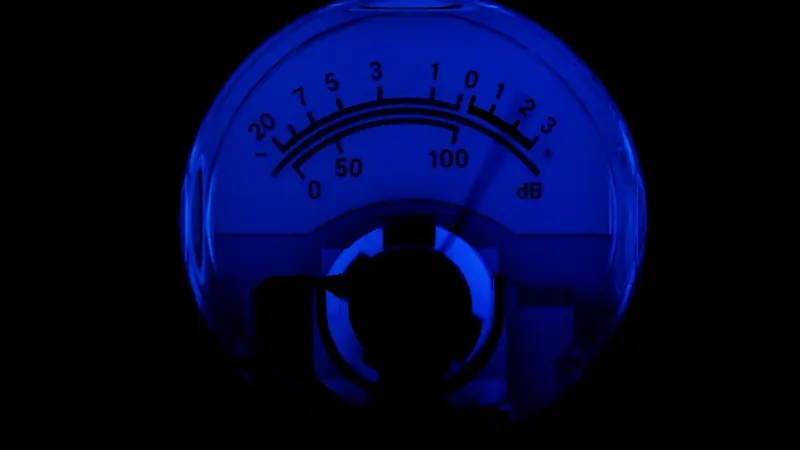 Mostrador analógico de nível de som, com escala em decibéis, iluminado em azul sobre fundo escuro