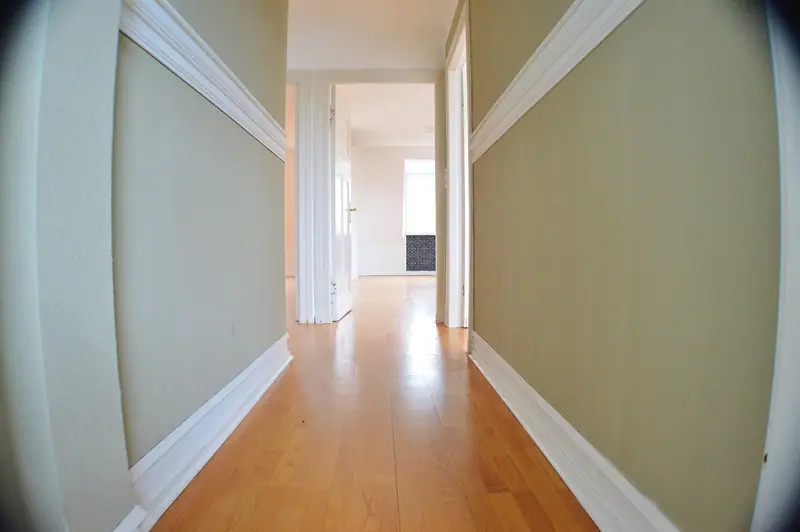 Corredor de apartamento com piso de madeira e portas brancas abertas dos dois lados