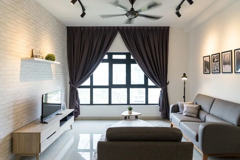 Sala de estar com sofá cinza e cortinas escuras e pesadas nas laterais de uma janela ampla