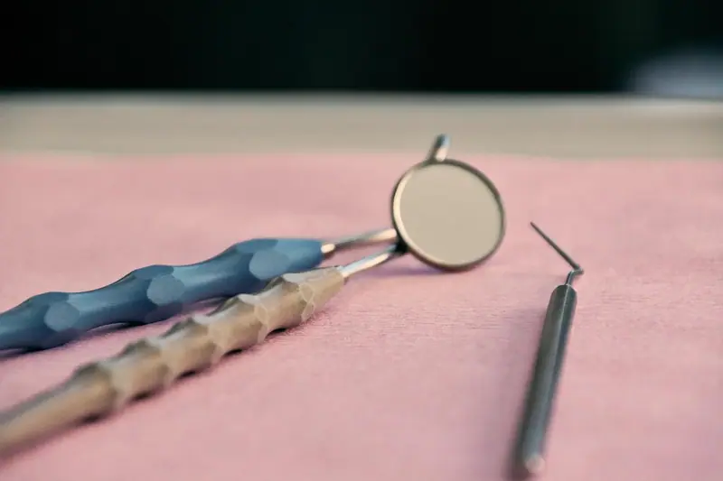 Espelho e sonda odontológicos sobre um tecido rosa, em close