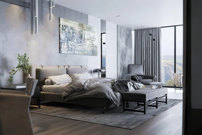 Quarto amplo com cama desarrumada, poltrona e cortinas cinza compridas junto a uma janela grande