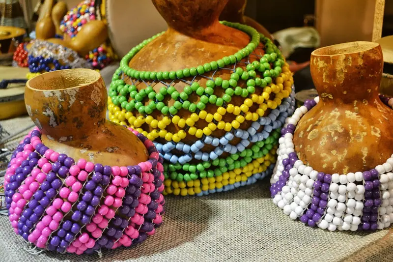Instrumentos de percussão feitos de cabaça, envoltos em redes de contas coloridas