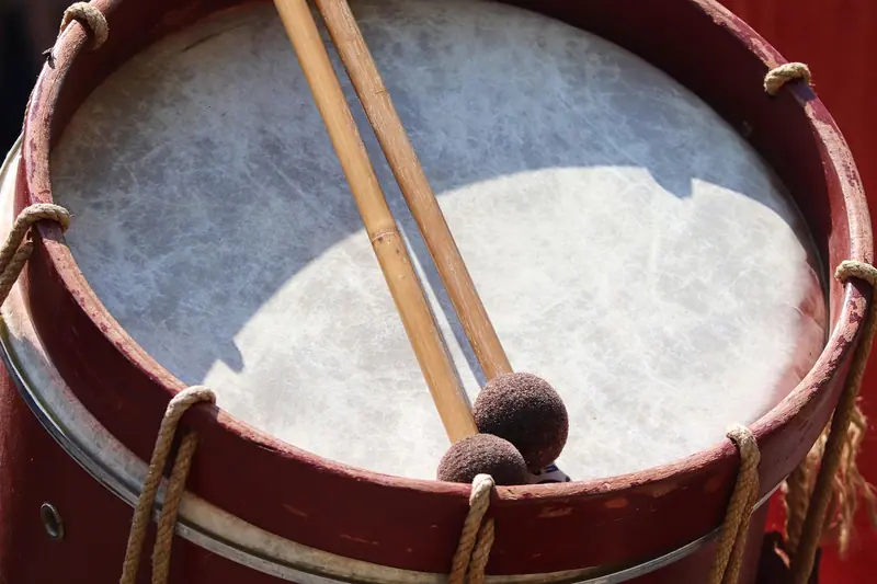 Tambor de corda com duas baquetas de ponta macia apoiadas sobre a pele