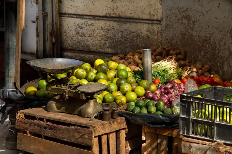 Banca com caixotes de madeira cheios de frutas e uma balança antiga em cima