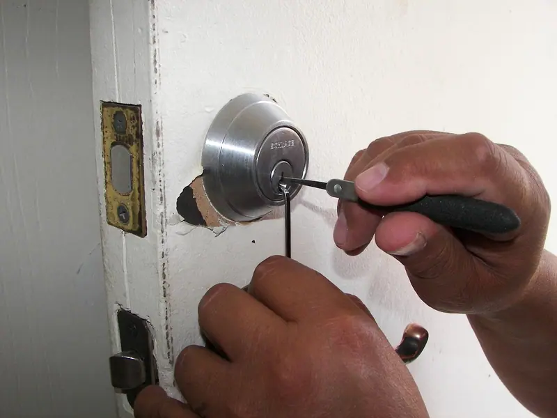 Mãos instalando uma fechadura com uma chave de fenda na borda de uma porta branca