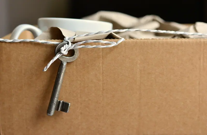 Chave antiga amarrada com barbante a uma caixa de papelão de mudança