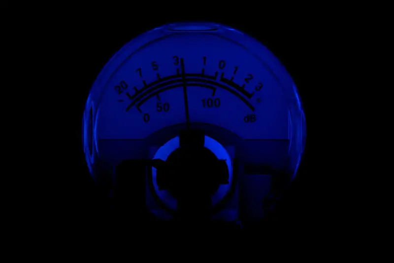 Mostrador analógico de nível de som iluminado em azul, sobre fundo escuro