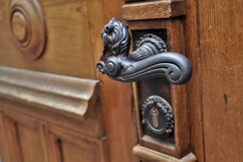 Maçaneta trabalhada de metal numa porta de madeira com detalhes entalhados